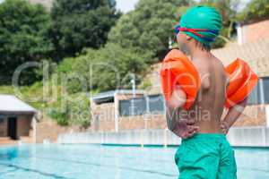 Boy wearing arm band standing at poolside