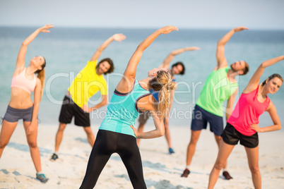 Friends stretching while standing on shore