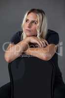 Thoughtful transgender woman leaning on chair