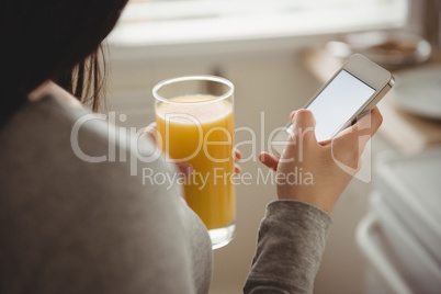 Close up of woman using smart phone while holding drink