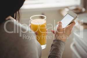 Close up of woman using smart phone while holding drink