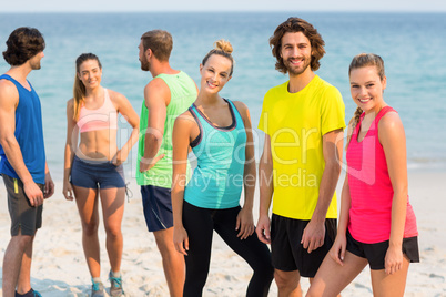 Friends in sportswear standing on shore at beach