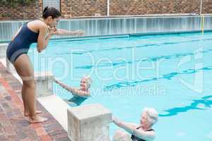 Swimming instructor assisting senior women