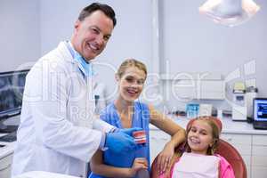 Dentist showing young patient how to brush teeth