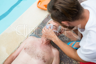 Lifeguard putting oxygen mask to senior man