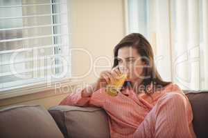 Woman drinking juice while looking through window