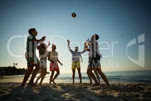 Friends playing volleyball on shore at beach