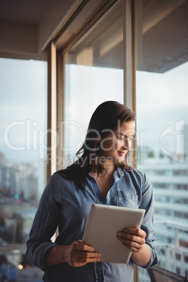 Woman holding tablet while looking through window