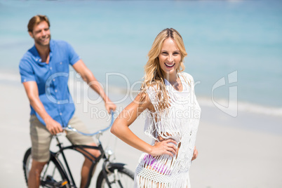 Woman by man riding bicycle at beach