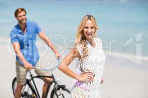 Woman by man riding bicycle at beach