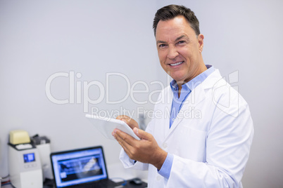 Portrait of happy dentist using digital tablet