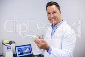 Portrait of happy dentist using digital tablet
