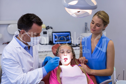 Dentist examining a young patient with tools