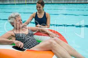 Trainer assisting senior woman on inflatable ring