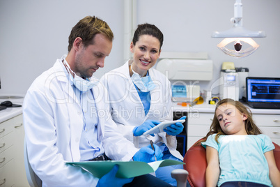 Dentists checking the reports while patient lying on dental chair