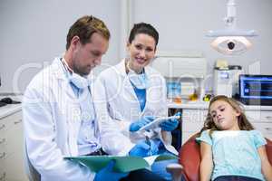 Dentists checking the reports while patient lying on dental chair