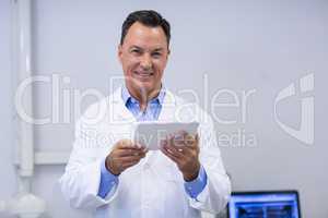 Portrait of smiling dentist holding digital tablet