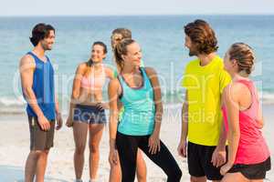 Friends in sports clothing talking while standing at beach