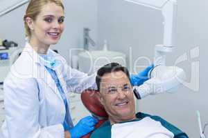 Portrait of dentist examining a male patient with dental tool