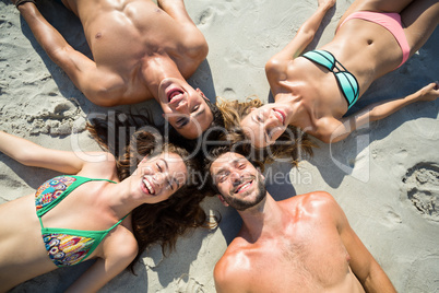 Smiling friends sunbathing on shore at beach