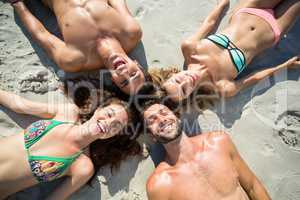 Smiling friends sunbathing on shore at beach
