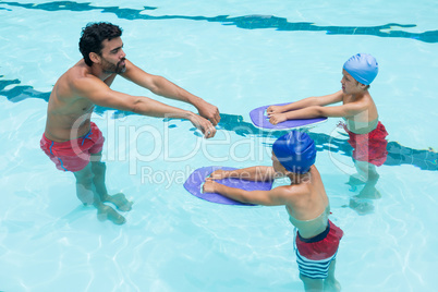 Coach assisting a kids in swimming in pool