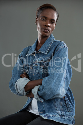 Androgynous man in denim jacket posing against grey background