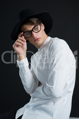 Androgynous man in hat posing with spectacles