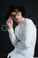 Androgynous man in hat posing with spectacles