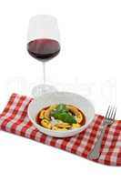Cooked tortelloni in bowl on napkin by wineglass