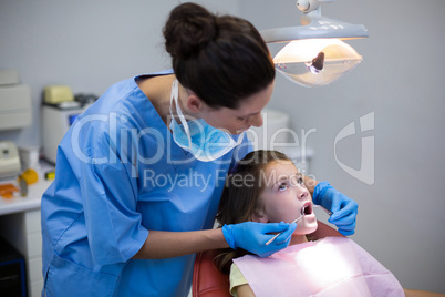 Dentist examining a young patient with tools