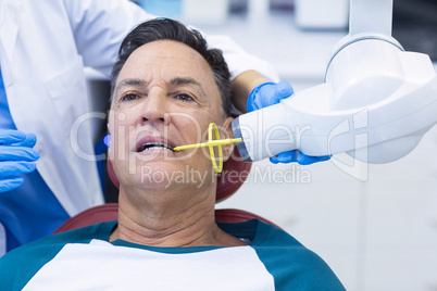 Dentist examining a male patient with tool