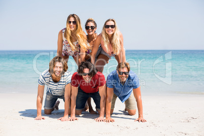 Cheerful friends forming pyramid at beach