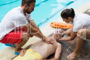 Lifeguards pressing chest of unconscious senior man