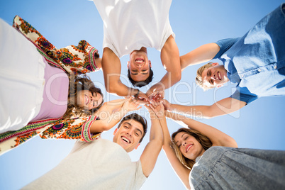 Directly below shot of friends huddling with arms raised