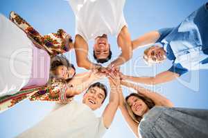 Directly below shot of friends huddling with arms raised