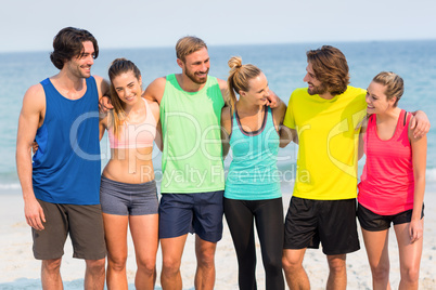 Friends standing with arm around at beach