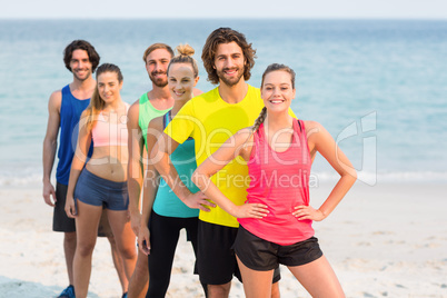 Happy friends in sports clothing standing at beach