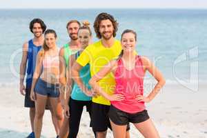 Happy friends in sports clothing standing at beach