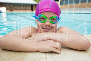 Portrait of young girl wearing swimming goggles in pool