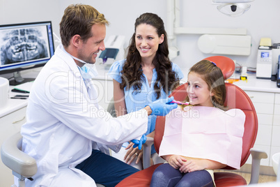 Dentist assisting young patient to brush teeth