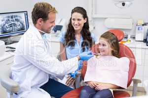 Dentist assisting young patient to brush teeth
