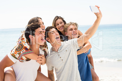 Friends taking selfie at beach on sunny day