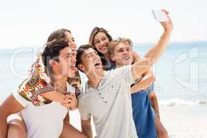 Friends taking selfie at beach on sunny day