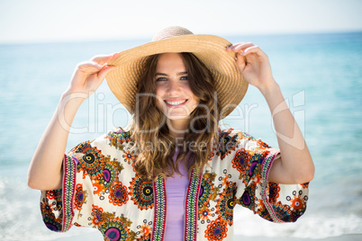 Happy young woman wearing hat while standing at beach