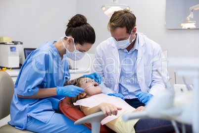 Dentist examining a young patient with tools