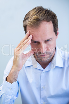 Close-up of tensed dentist sitting with hand on forehead