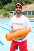 Lifeguard standing with rescue buoy near poolside