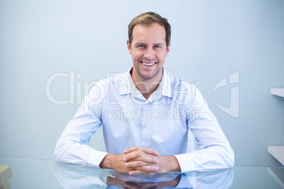 Portrait of happy dentist sitting at desk