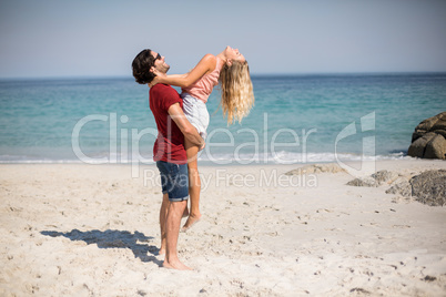 Boyfriend carrying girlfriend while standing at beach